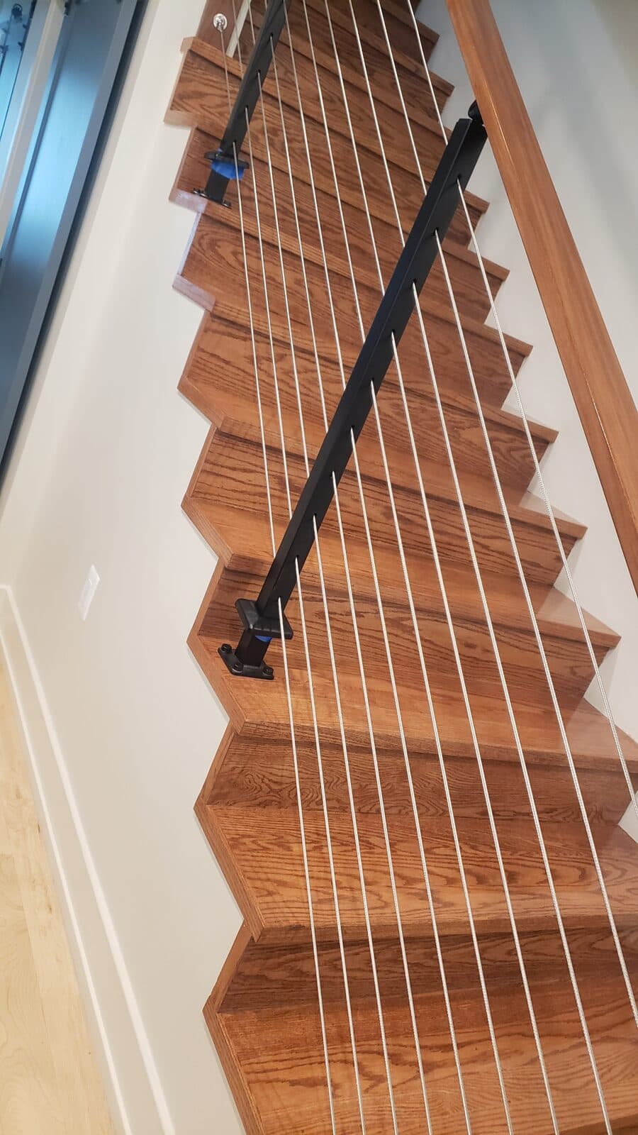 Brown stained staircase with custom handrail by Ventura